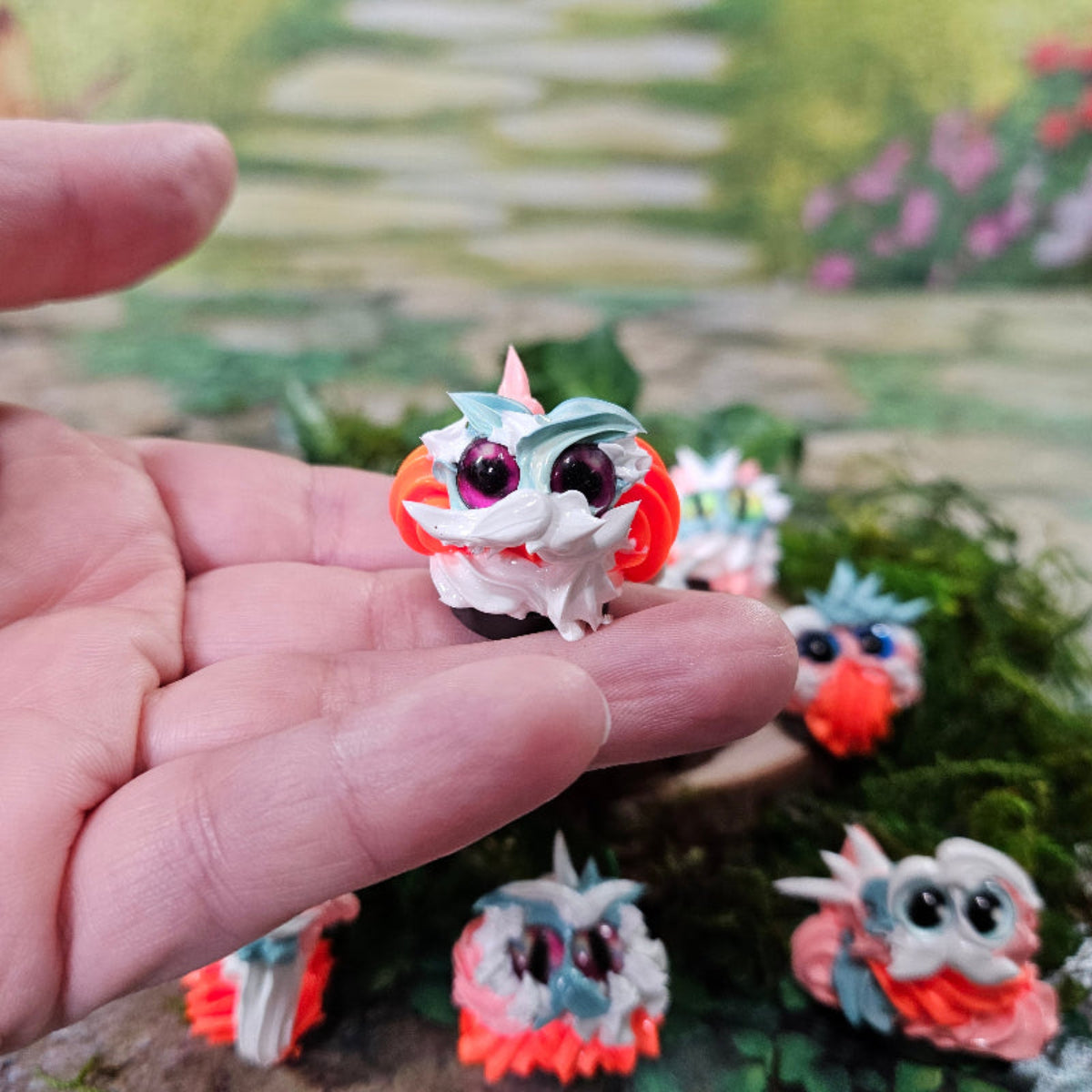 Hand holding an orange, white and aqua Citrus Whip Squirklee