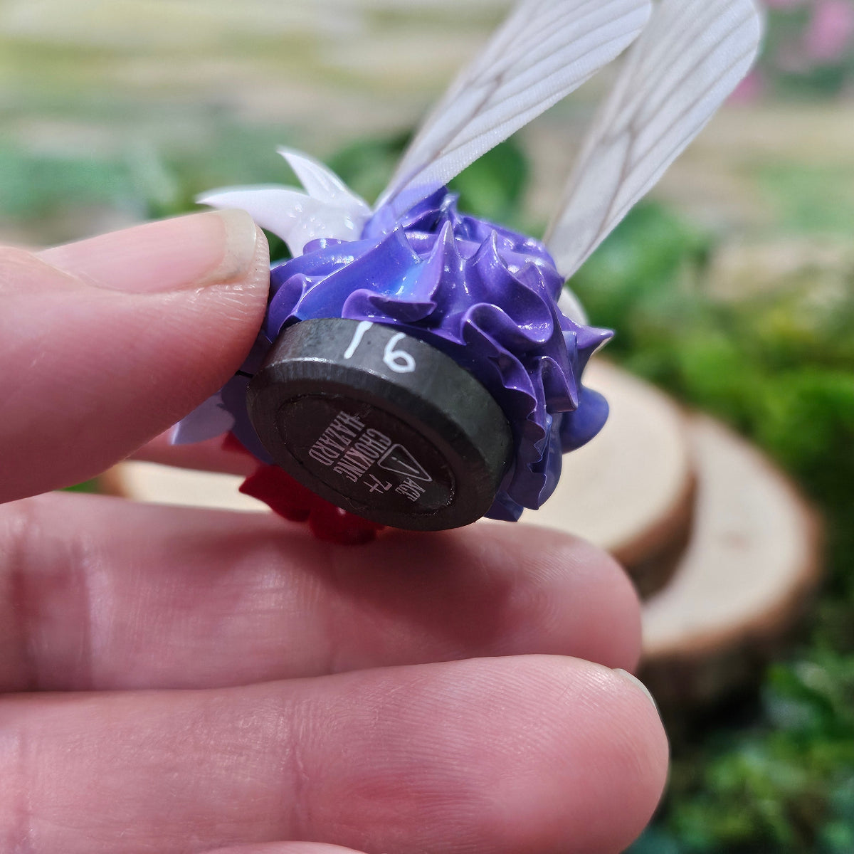 Hand holding a hand-made frosting creature called a Squirklee. The backside of the Squirklee is visible, showing hand-numbered detail.