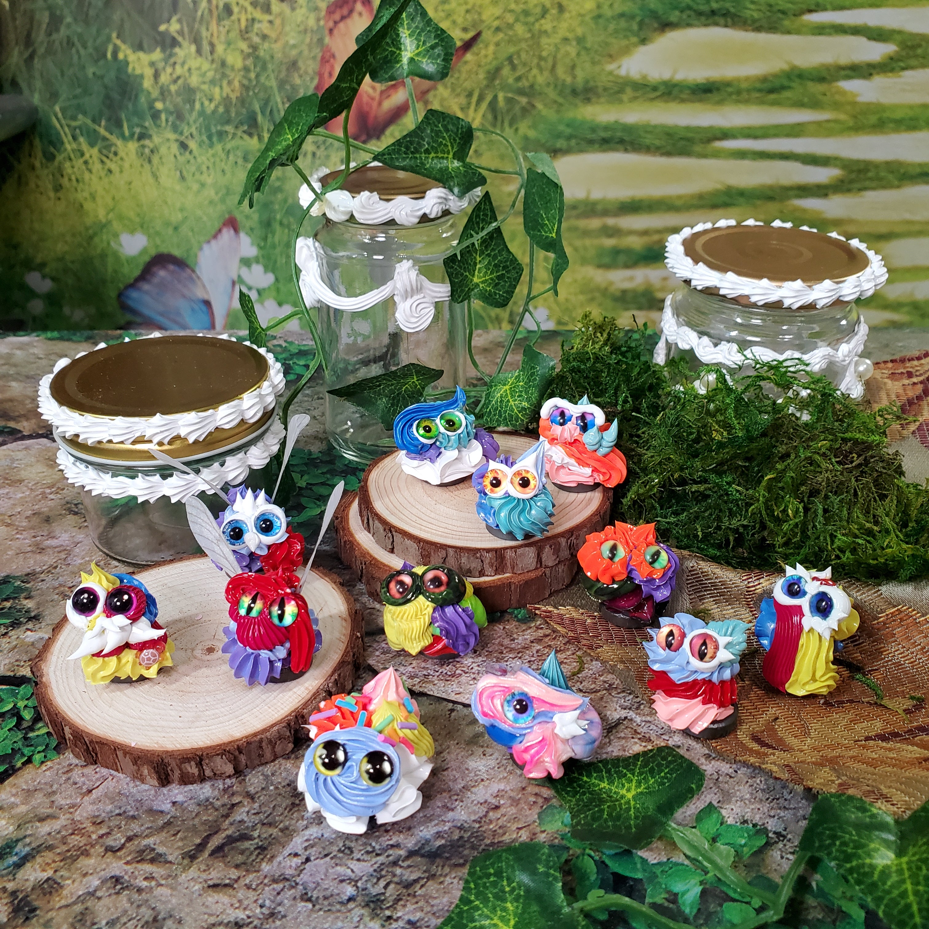 Colorful frosting creatures sitting on wooden slices with clear metal-topped frosted jars with a natural background