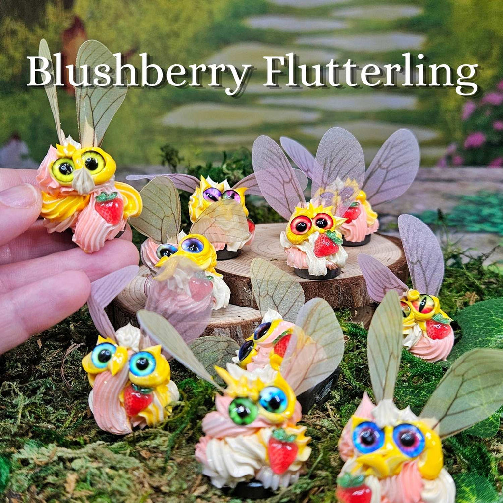 group of pink, yellow and cream strawberry themed winged frosting creatures sitting in grass
