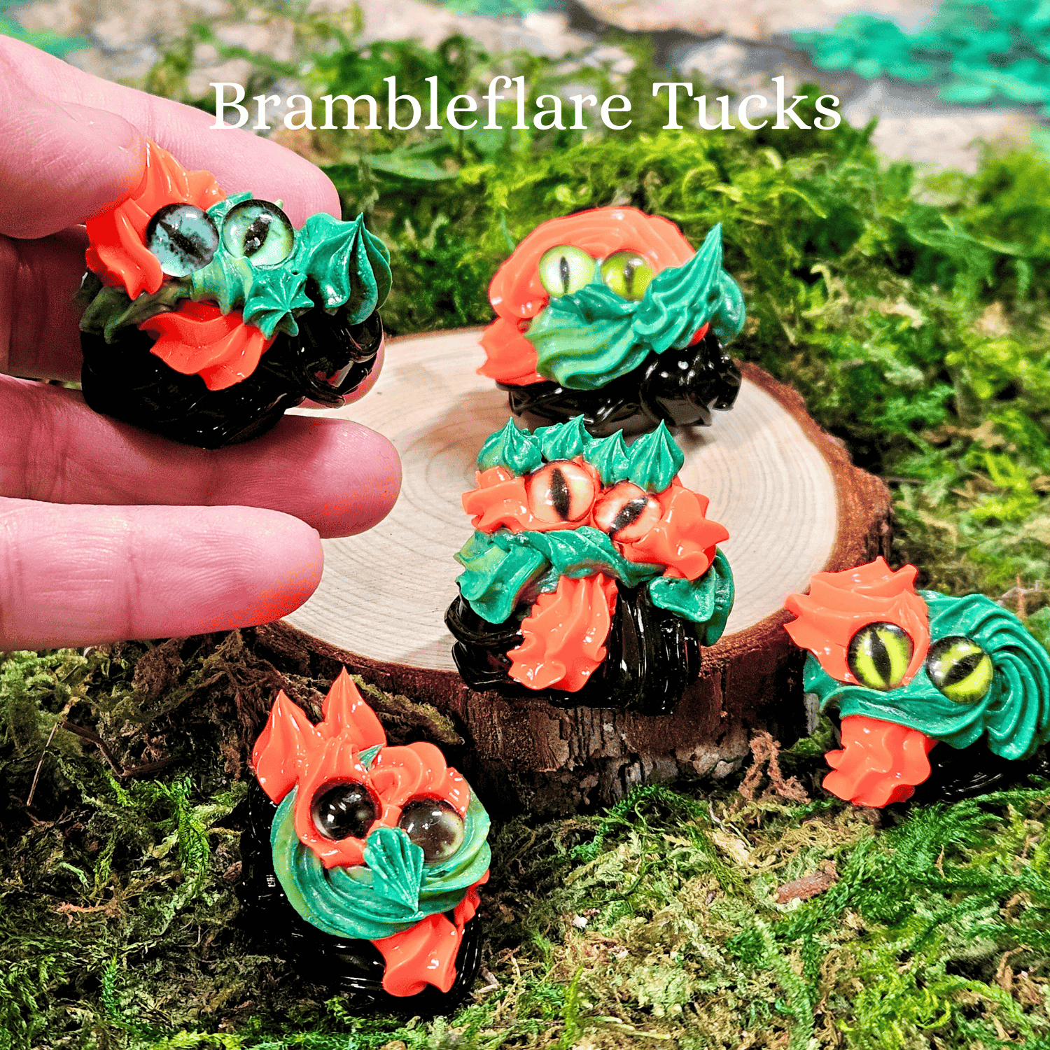 Frosting creatures with colorful designs on a wooden log and green moss background, featuring the brand 'Brambleflare Tucks'.