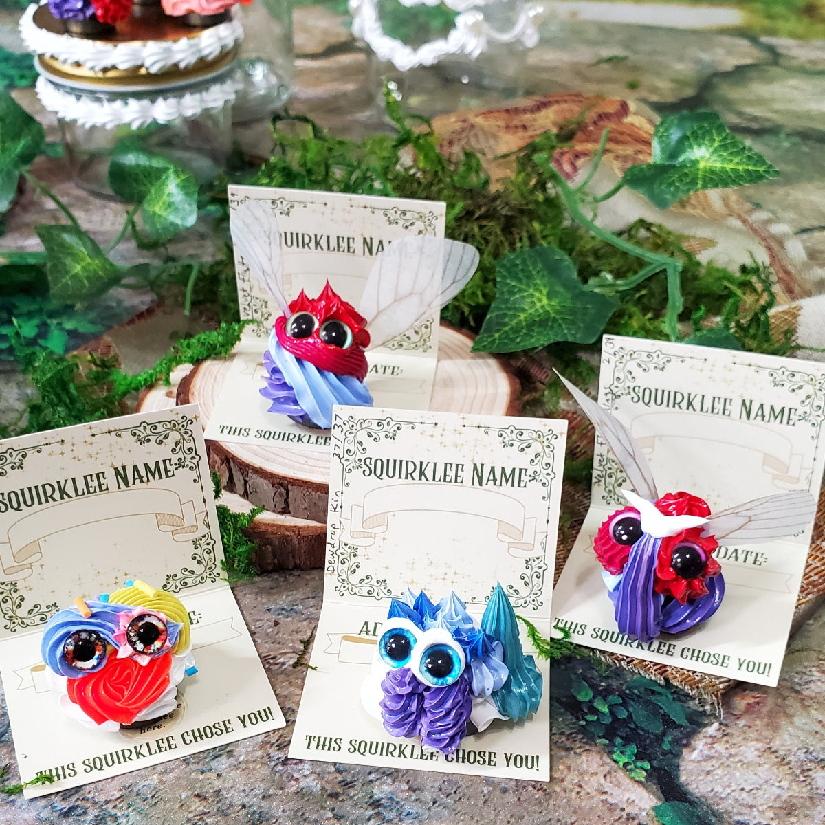 Four separate very colorful tiny Squirklees, each sitting on their own adoption card. 