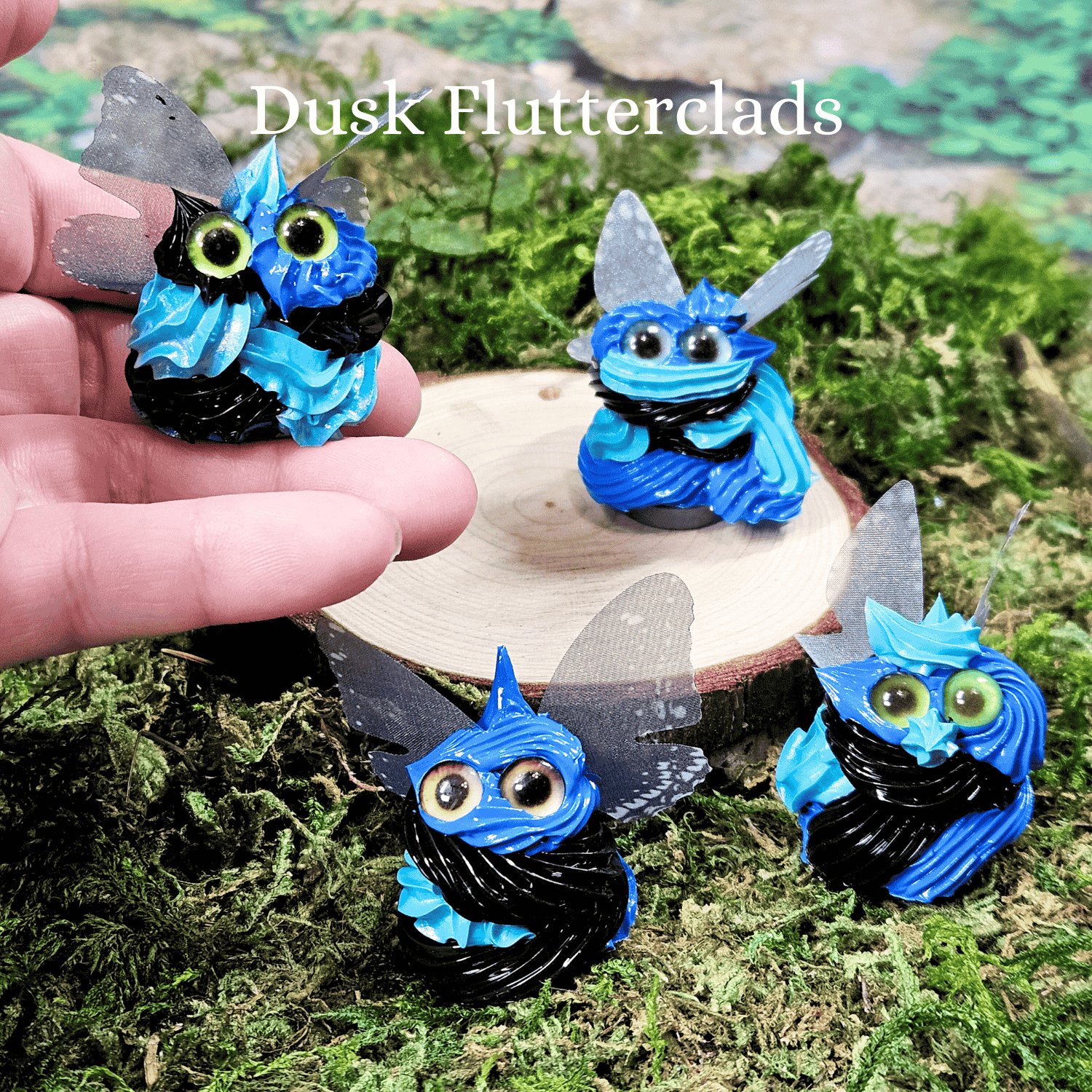 Blue and black winged frosting creatures with green eyes on a natural background