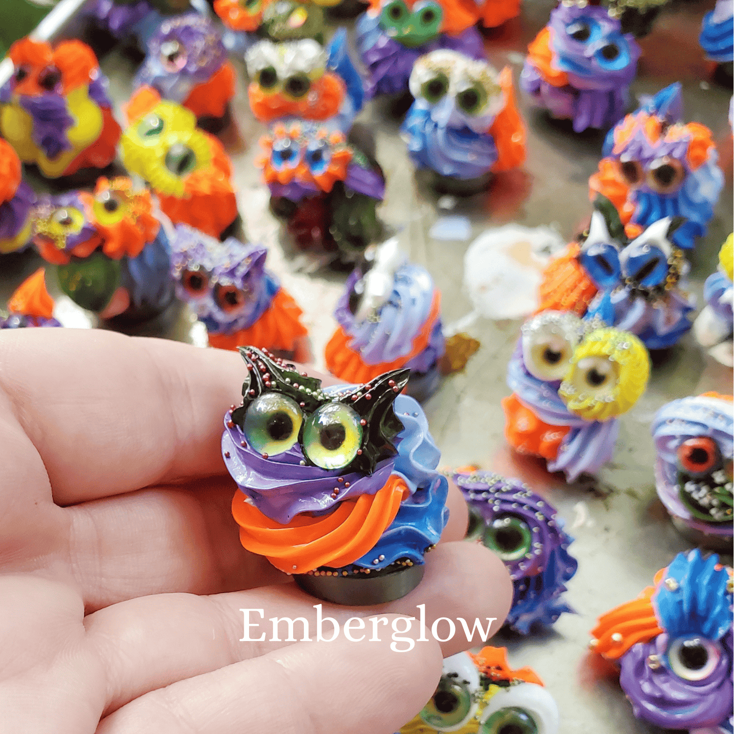 Colorful frosting creature held by a hand with 'Emberglow' branding.