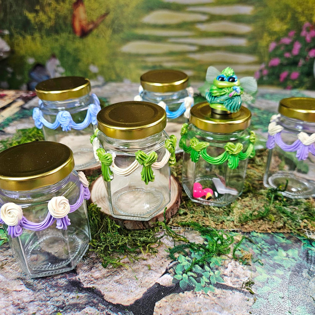 glass jars with piped paint that looks like frosting, in various colors, a frosting creature sits atop one jar with green frosting trim