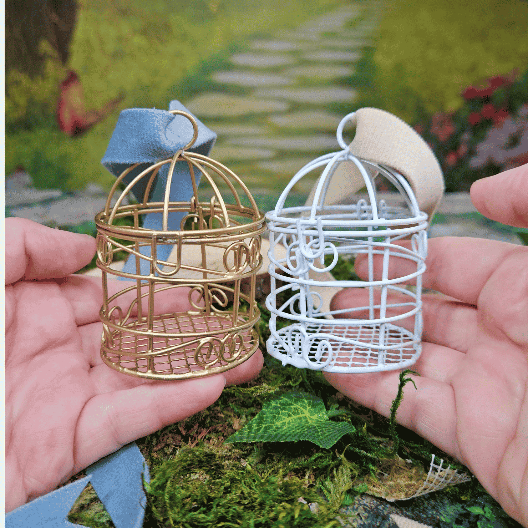 Two miniature wire cages, one gold and one white, held in hands with a garden background.