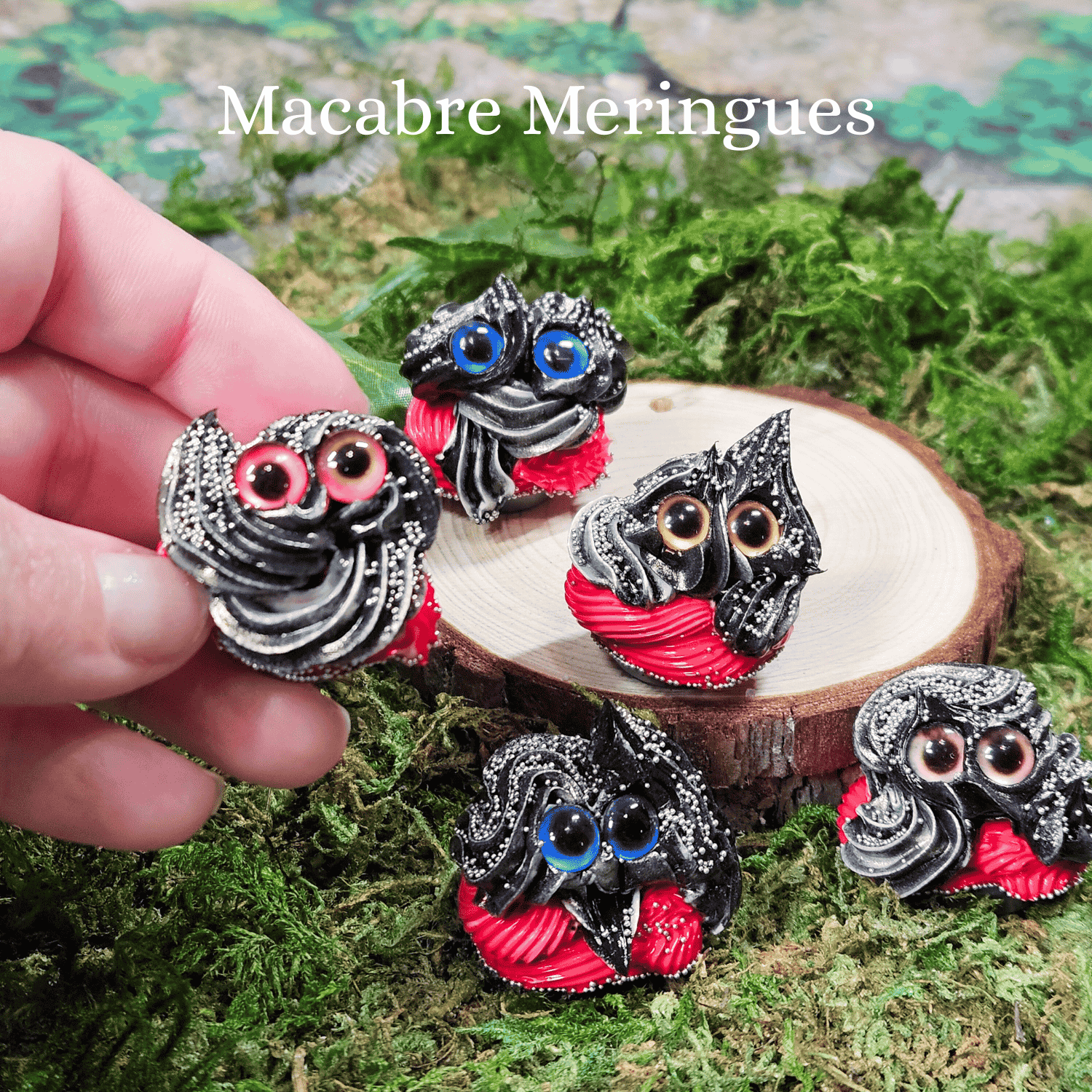 Decorative frosting creatures with red accents on a wooden stand, held by a hand on a green moss background with 'Macabre Meringues' text.