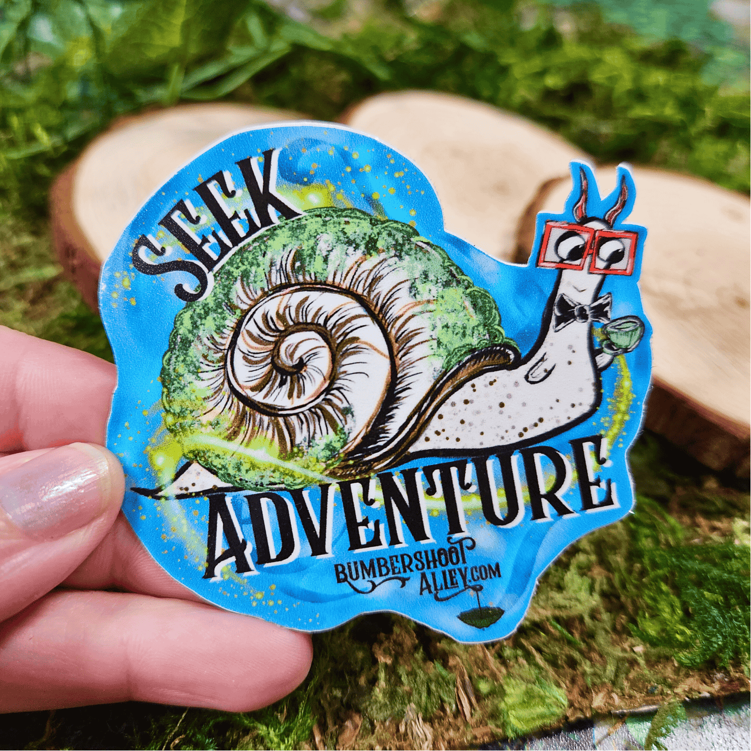 Sticker with a snail and 'Seek Adventure' text held by a hand on a natural background