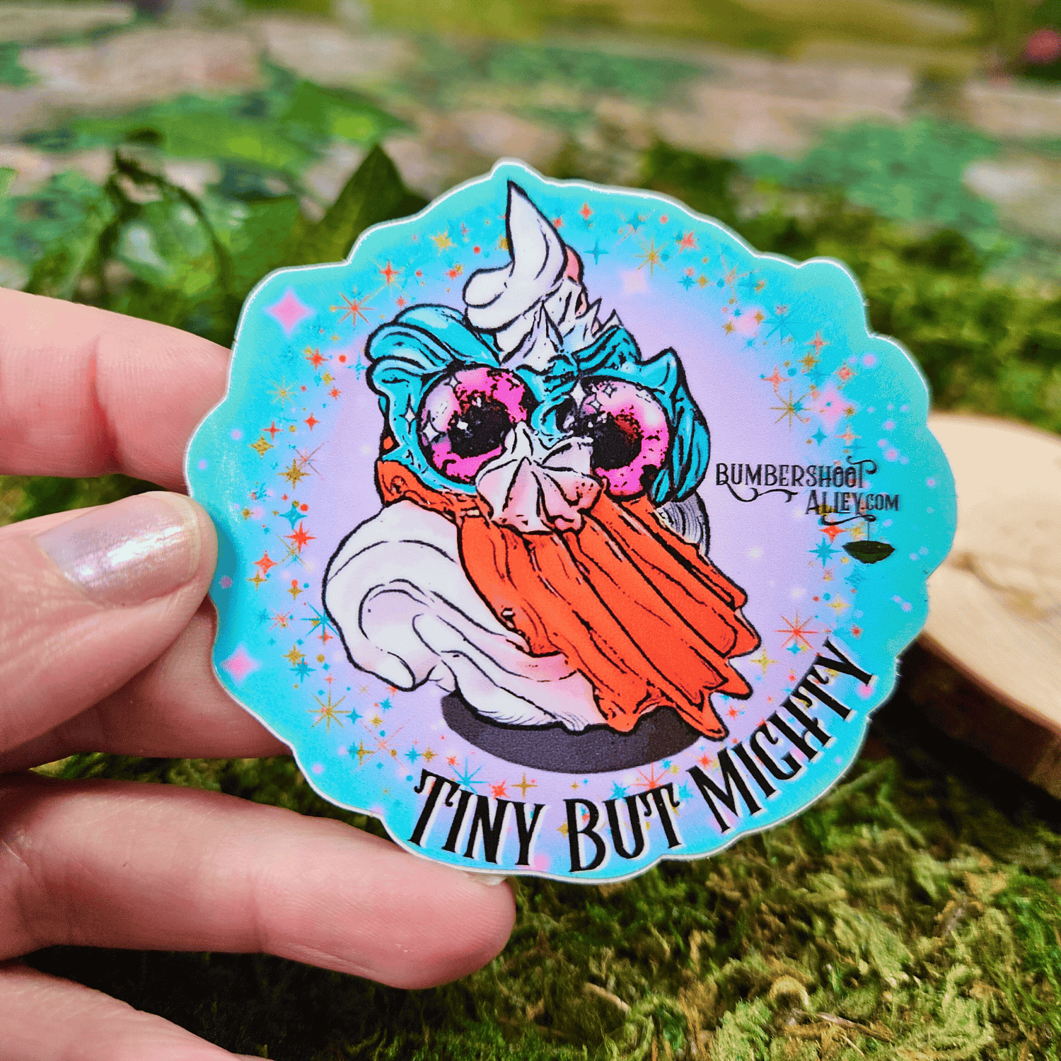 Sticker with a colorful design of a frosting creature, held by a hand against a natural background.