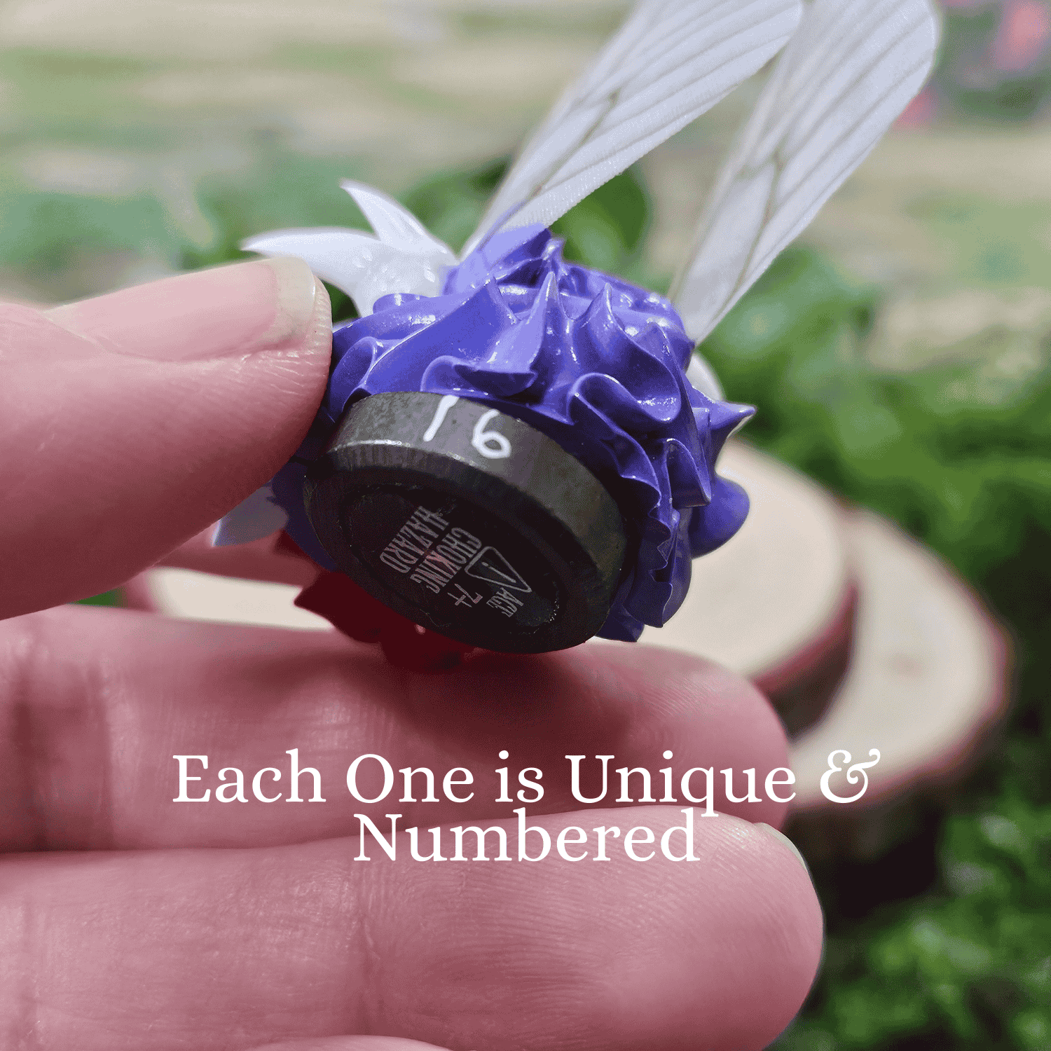 Hand holding a unique numbered frosting creature with a blurred natural background