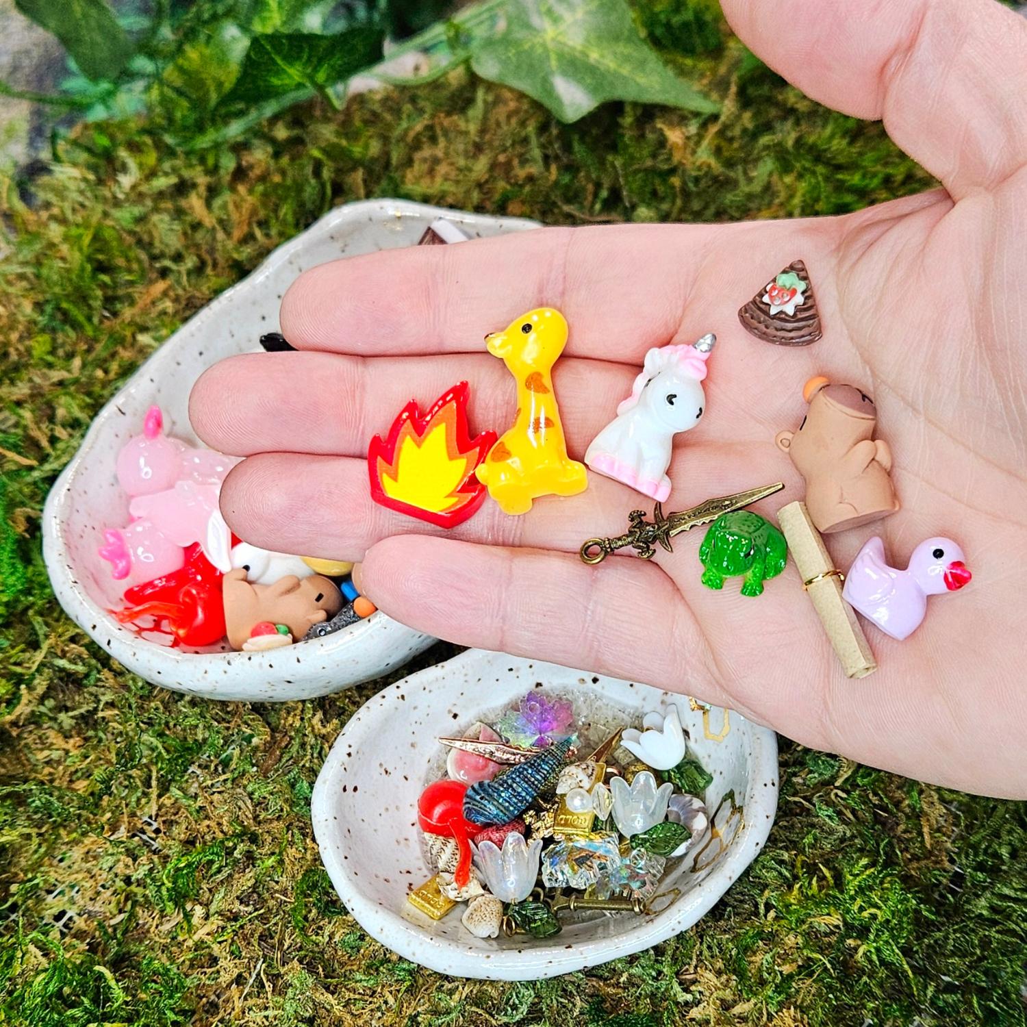 miniature fire, giraffe, unicore, dagger, frog, pie, capybara, scroll and lavender duck in a hand