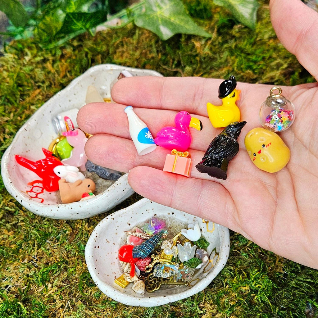 miniature surprise treasures for squirklees to guard, a hand holding a miniature milk, flamingo, grow, positive potato, pirate duck, potion bottle, present
