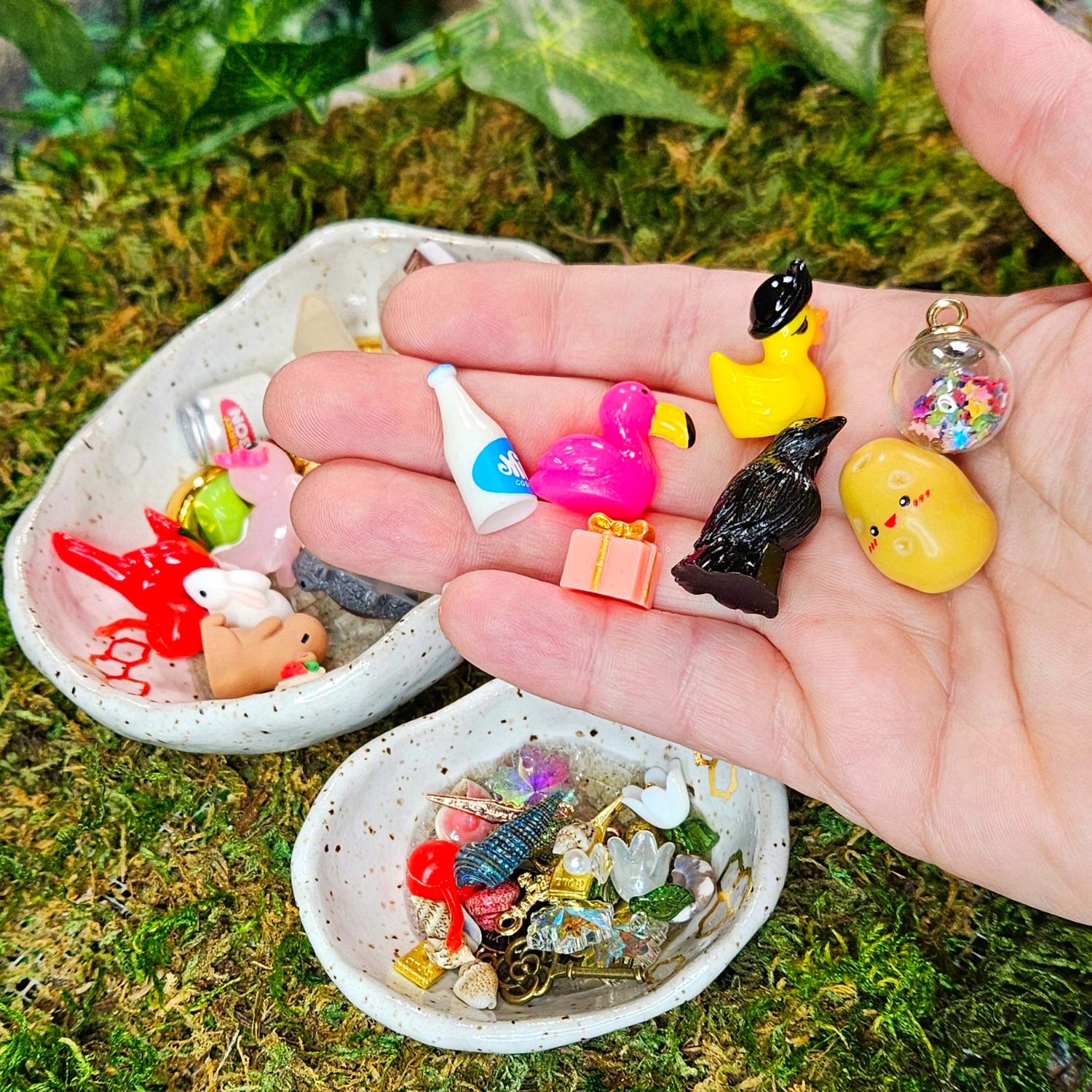 miniature surprise treasures for squirklees to guard, a hand holding a miniature milk, flamingo, grow, positive potato, pirate duck, potion bottle, present