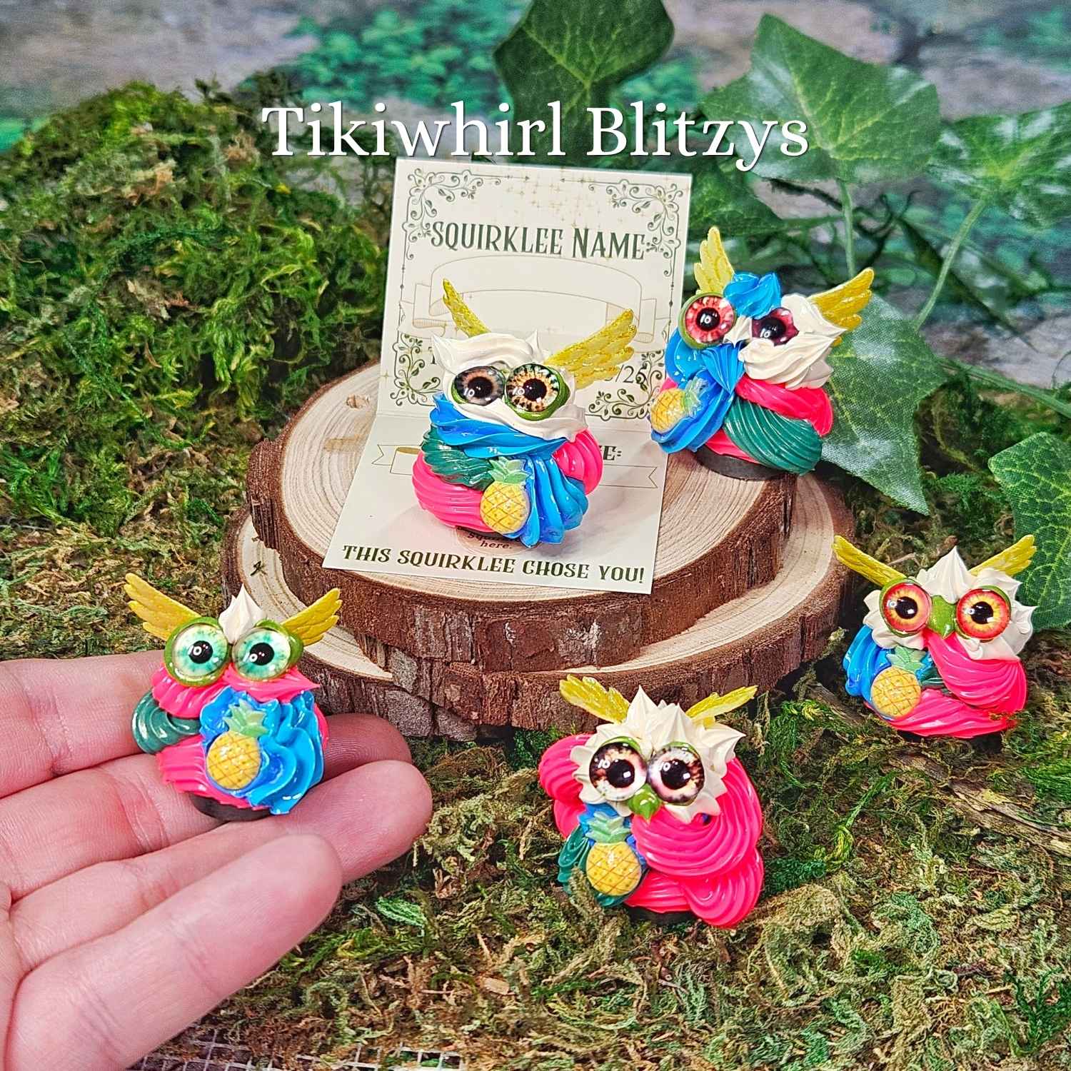closeup of tiny frosting creatures called squirklees, this is a family that is hotpink, blue, green with yellow wings, family name is Tikiwhirl Blitzy