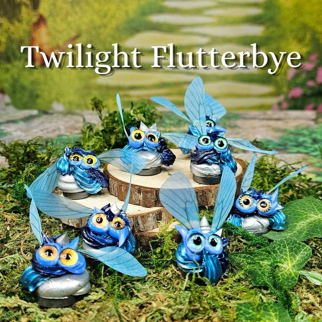 group of blue and silver frosting creatures with wings sitting in grass